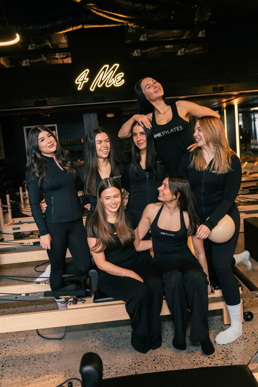 The 4ME Pilates team together on the reformers, smiling.